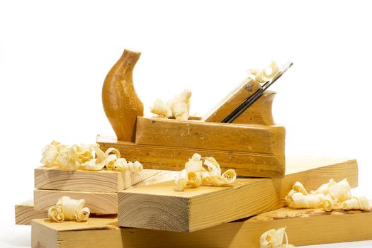 Wooden plane, boards and planed wood shavings on a white background