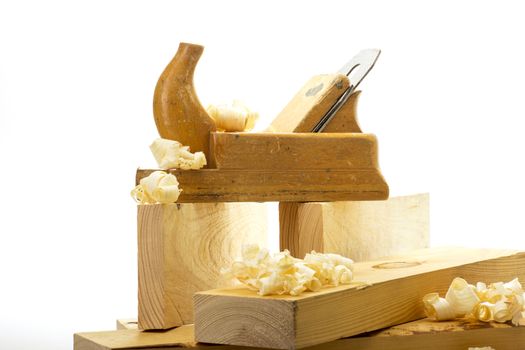 Wooden plane, boards and planed wood shavings on a white background