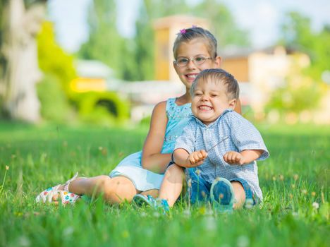 Portrait of little boy and his sister having fun in the summer park
