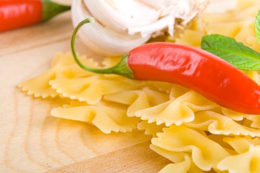 Golden raw dried Italian pasta with other ingredients on kitchen desk.