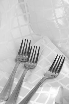 Shiny stainless steel forks on white fabric