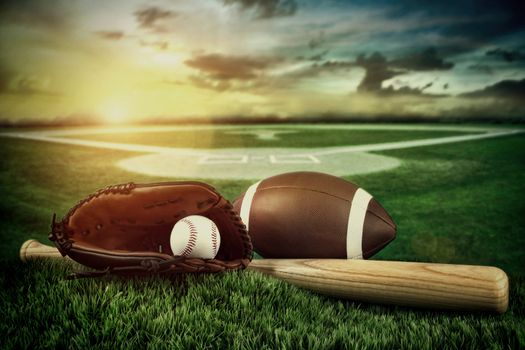 Baseball, bat, and mitt with field in background at sunset