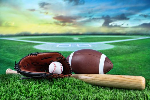 Baseball, bat, and mitt with field in background at sunset