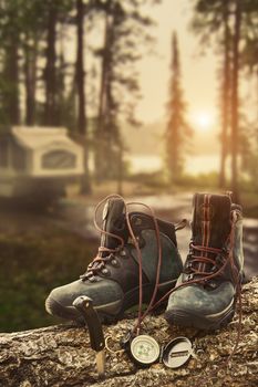 Hiking boots with compass on tree trunk at campsite