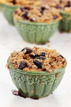 An autumn pumpkin souffle with a streusel and raisin topping in small ramekin. 
