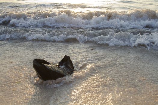 piece of wood sticking out of the sand about to be hit by waves