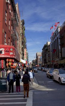 shoppers waiting at street corner in front of a souvenir store in New York Chinatown