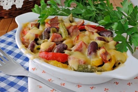 Beans with ham and vegetables, baked with cheese on the plate