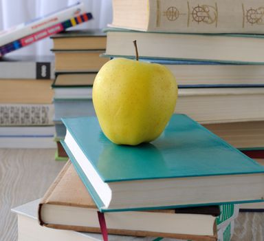 Apple on stack of books on the table among the other books