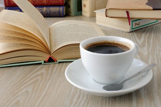 a cup of freshly brewed coffee on a table with books