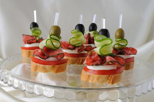 Canape of the baguette with salami on a glass base