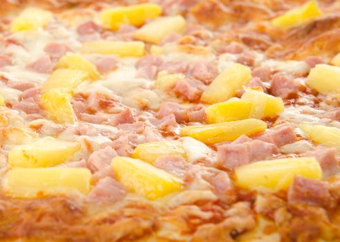 Closeup of a cooked hawaiian pizza with pineapple and ham.