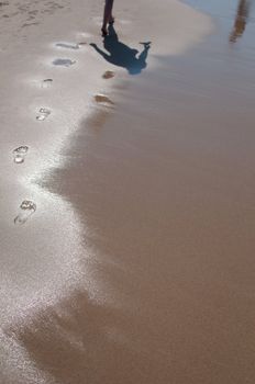 Woman walking barefoot on sunny beach in summer day