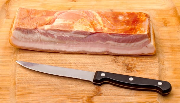 Boiled-Smoked Bacon with knife on cutting board