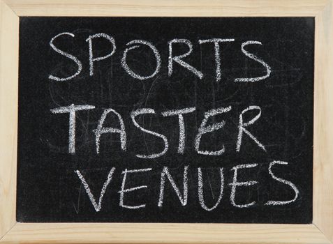 A blackboard with a wooden border with the words 'SPORTS TASTER VENUES' written by hand in white chalk.