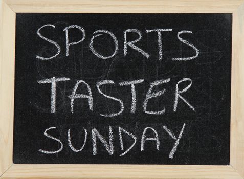 A blackboard with a wooden border with the words 'SPORTS TASTER SUNDAY' written by hand in white chalk.