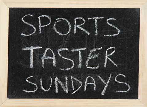 A blackboard with a wooden border with the words 'SPORTS TASTER SUNDAYS' written by hand in white chalk.