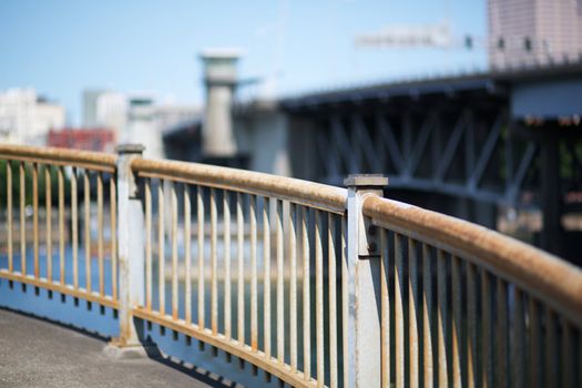 Curved steel railing with soft focus bridge and sky in Portland Oregon