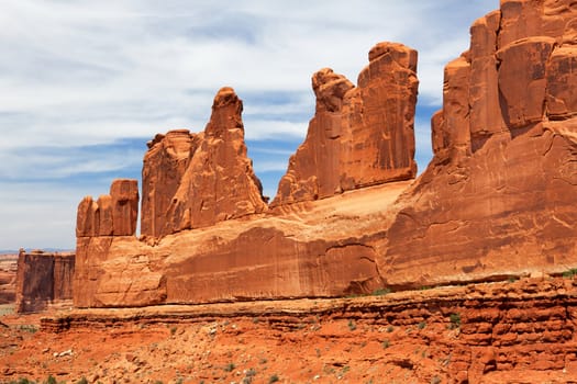 Right side of National Park Avenue with high redstone walls along diagonal with blue wispy cloud sky