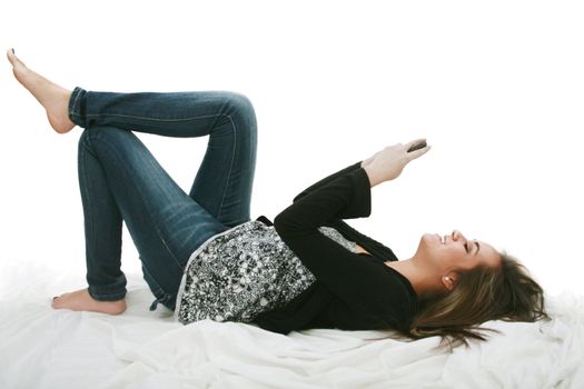 Relaxed young woman sending a text message lying on the bed