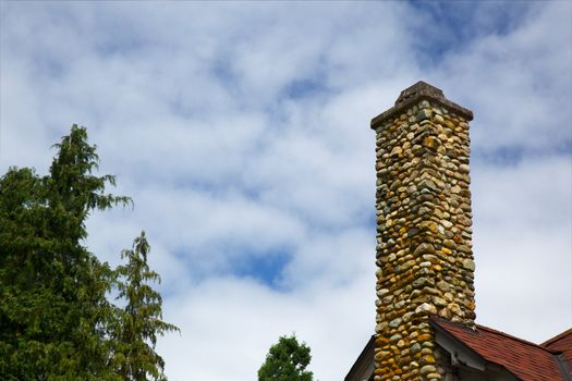 Multi-color stone chimney against a puffy clouded sky