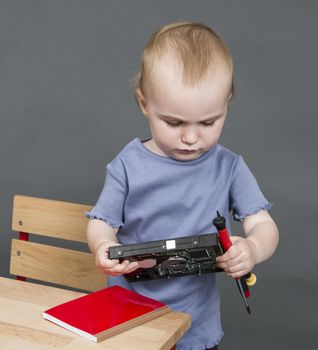 child with hard drive and tools in grey background