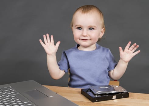 child with open hard drive and laptop computer in grey background