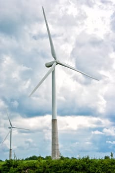 Two wind turbines on a cloudy sky background