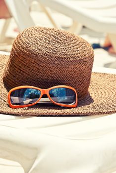 Straw hat with sunglasses on the longue
