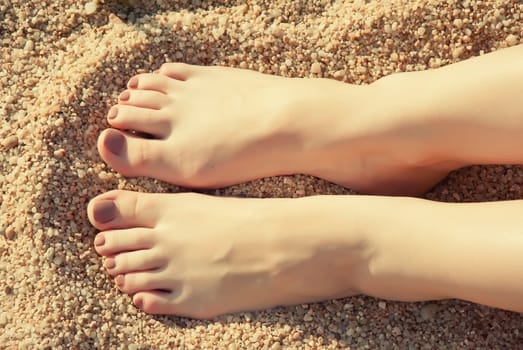 Close up female feet at sandy beach