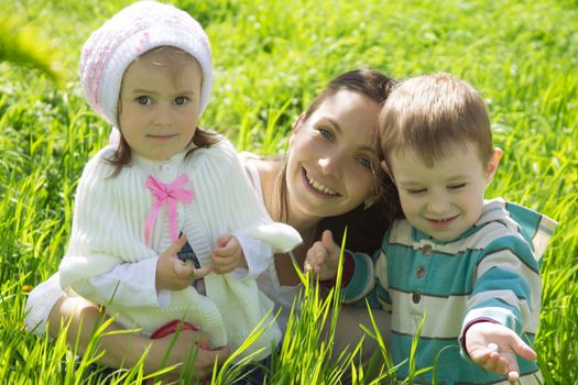 Happy mother with two children among green grass