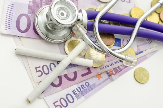 Top view of cigarettes and stethoscope on Euro money on white desk.  Concept of health and financial damage smoking makes.