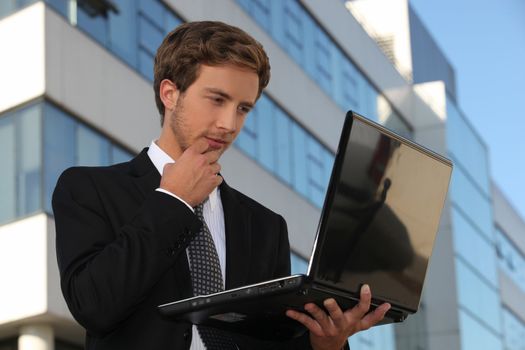 Handsome businessman using a laptop in the city