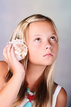 Young girl with shell listening to the sea