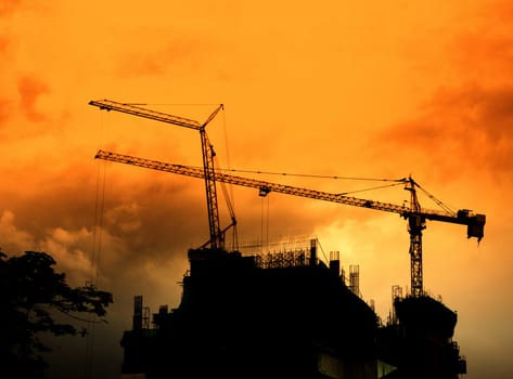 Crane on tower in construction site silhouette with sunset sky