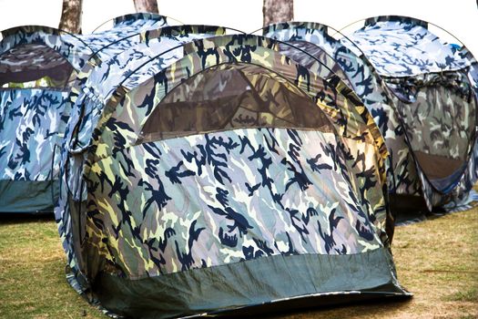 A small canvas tent military pattern is placed on the lawn at the resort.