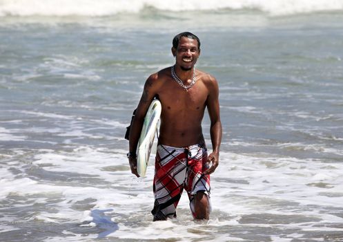 Man-surfer with board on a coastline. Bali. Indonesia