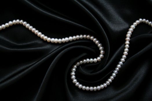 White pearls on the black velvet background 