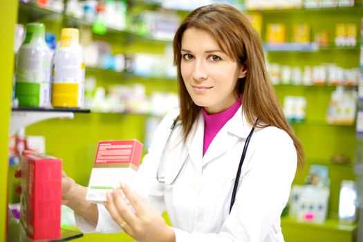 happy doctor working in pharmacy with medicine in her hand