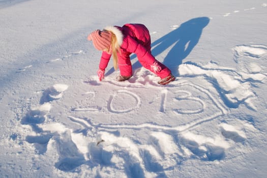 a little girl writes 2013  in the snow 