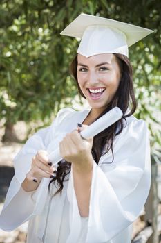 Attractive Mixed Race Girl Celebrating Graduation Outside In Cap and Gown with Diploma in Hand.