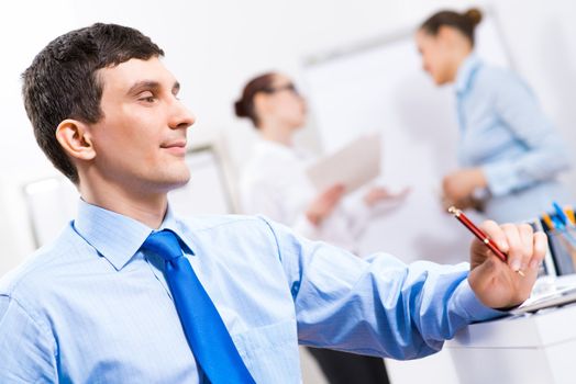 Portrait of a businessman in a blue shirt in the background of colleagues discussing