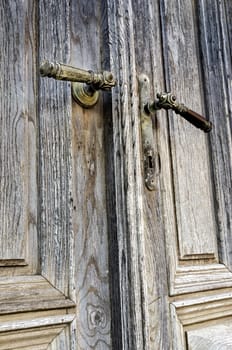 Old decorated door handles on weathered doors.