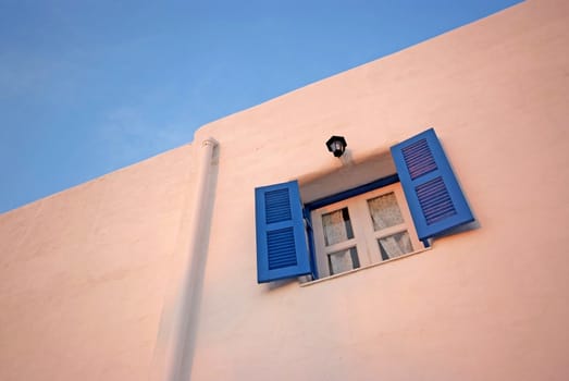 Vintage blue windows on the white wall and blue sky.