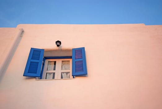 Vintage blue windows on the white wall and blue sky.