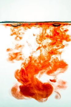 Red ink in colored water on white background.