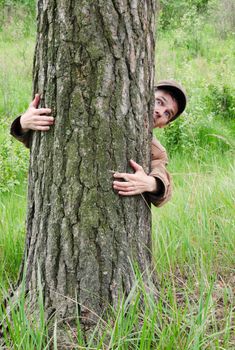 Man hugging tree with fear on face