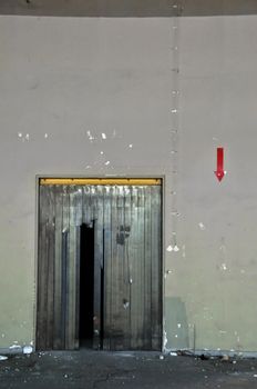 Door and arrow sign in abandoned factory. Abstract industrial interior.