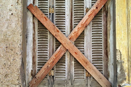 Boarded up old window and peeling paint weathered wall. Abandoned house detail.
