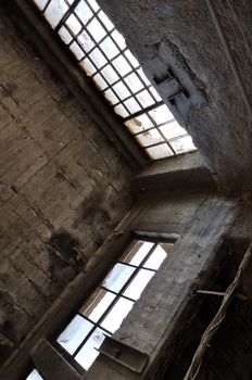 Broken windows concrete wall and ceiling in derelict factory. Industrial architecture.